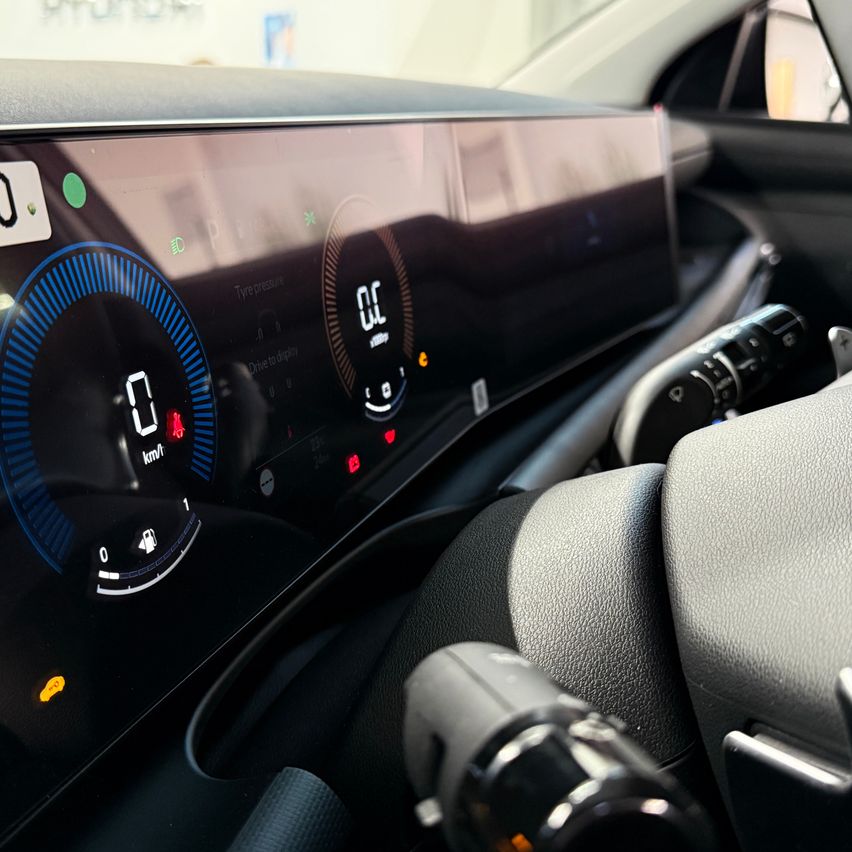 Das Armaturenbrett eines Autos zeigt ein digitales Display mit Tachometer und anderen Anzeigen, einem Kontrollschalter und einem Lenkrad.