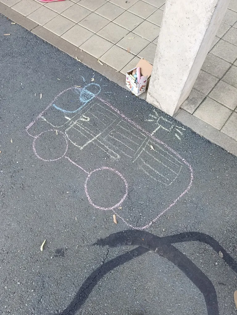 Eine Kreidezeichnung eines Fahrzeugs auf der Straße mit einer Schachtel Kreide in der Nähe.
