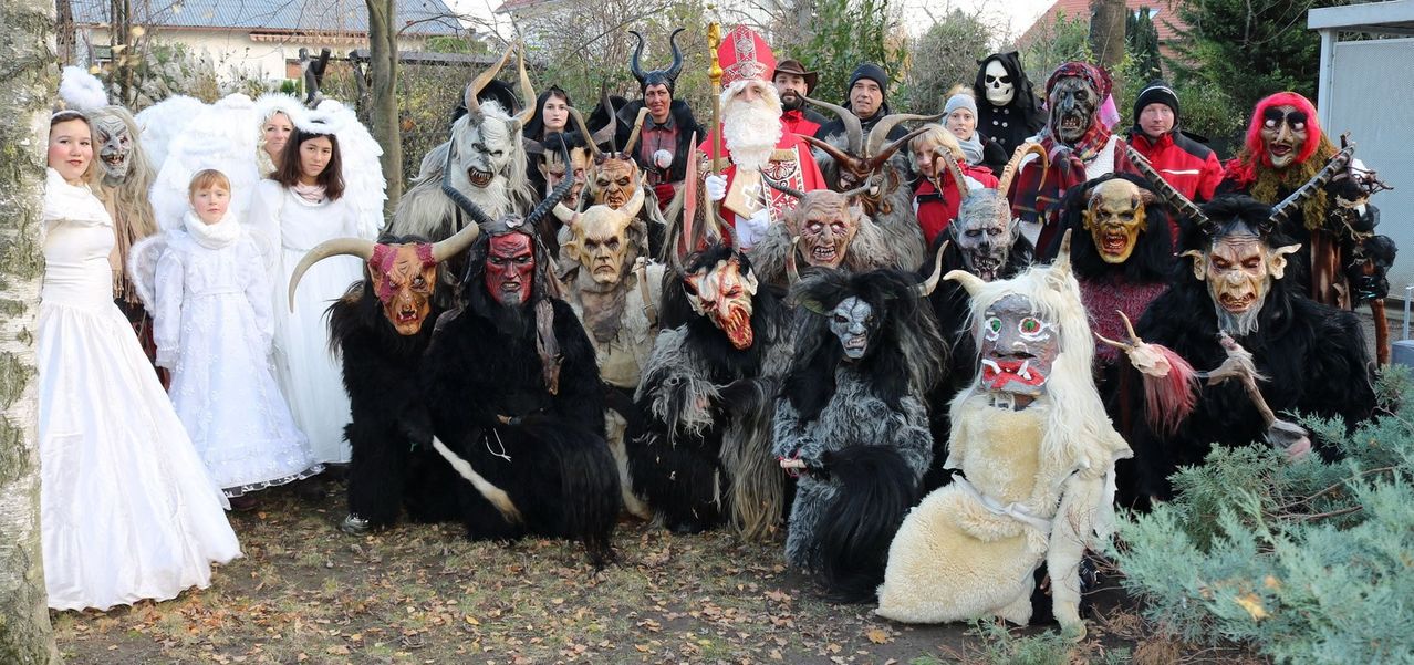 Eine Gruppe von Menschen in Kostümen, die für ein Foto posieren, einige tragen Masken und Hörner, möglicherweise für ein Halloween-Event.