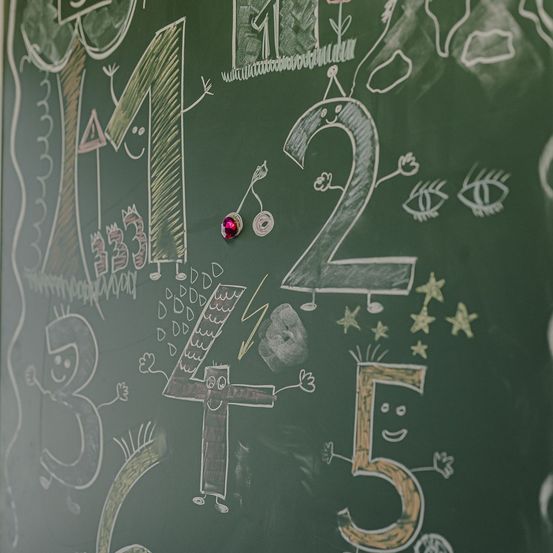 Eine Tafel mit den Zahlen 1 bis 5 und verschiedenen Zeichnungen, darunter ein lächelndes Gesicht, Sterne und eine rote Nadel.