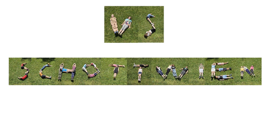 Children lying on grass in a line form the letters of the word PLAY.