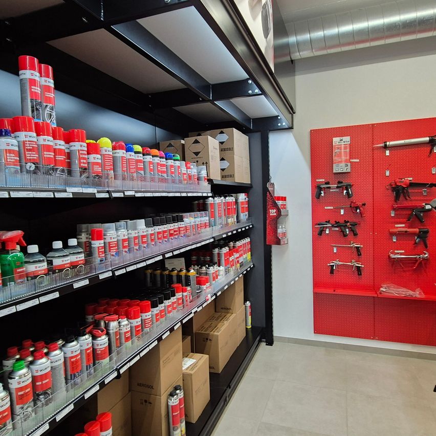 Innenansicht eines Ladens mit Regalen voller Sprühdosen, Kisten und einer roten Pinnwand, die verschiedene Werkzeuge zeigt.