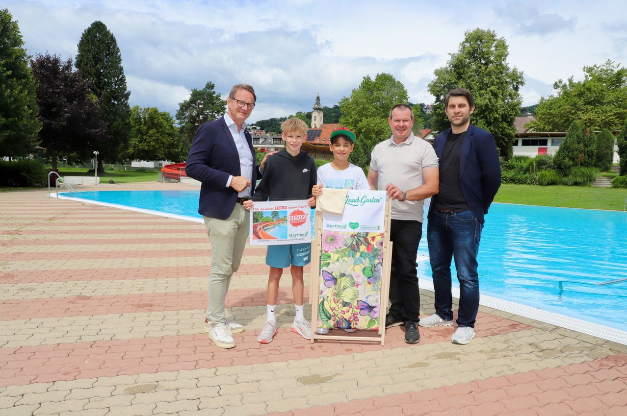 Fünf Männer und zwei Jungen stehen am Pool. Die Männer halten Urkunden. Die Jungen halten einen Schmetterlingsdruck und ein Schild mit einem Baum darauf.