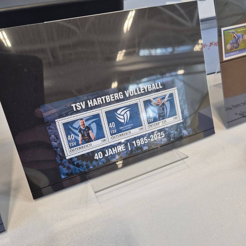 Ein Glasdisplay zeigt Briefmarken für TSV Hartberg Volleyball. Es erinnert an 40 Jahre von 1985 bis 2025. Die Briefmarken zeigen Spieler in Aktion.
