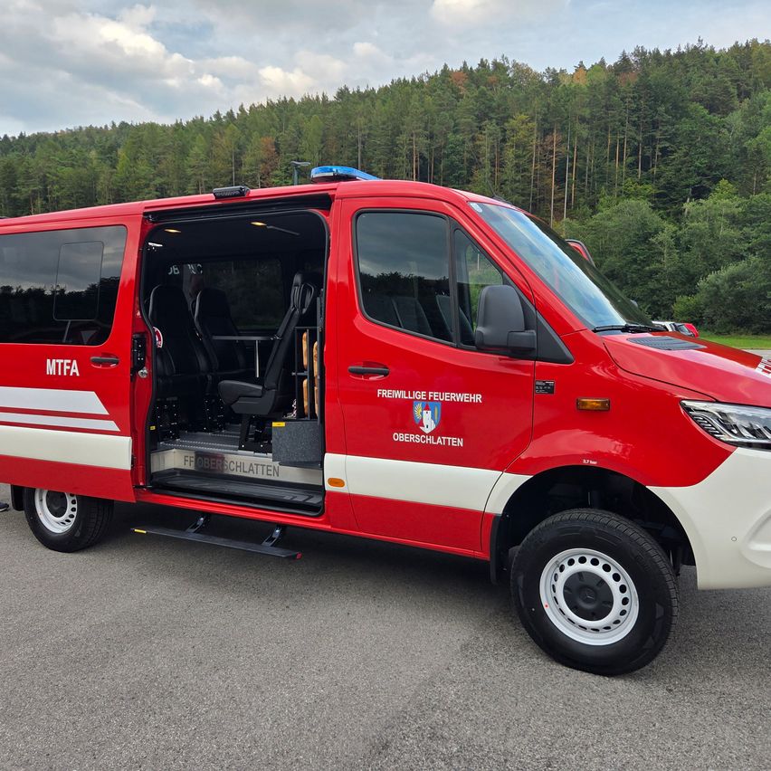 Ein rotes Notfallfahrzeug mit der Aufschrift Freiwillige Feuerwehr Oberschlatten an der Seite und offenen Türen.