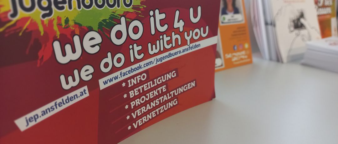 Ein rotes Plakat mit dem Titel Gendburo und weißem Text 'Wir machen es für dich' mit Kontaktinformationen und Social-Media-Symbolen.