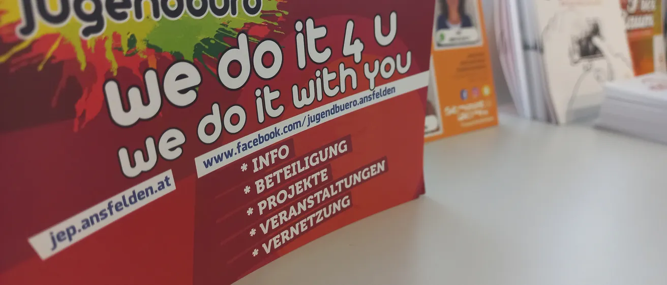 Ein rotes Plakat mit dem Titel Gendburo und weißem Text 'Wir machen es für dich' mit Kontaktinformationen und Social-Media-Symbolen.