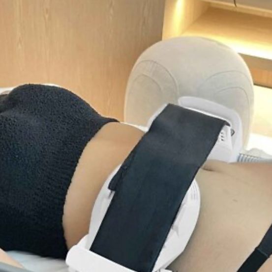 Eine Person liegt auf einem Bett und trägt eine schwarze Shorts und eine weiße Knieorthese mit schwarzen Riemen.