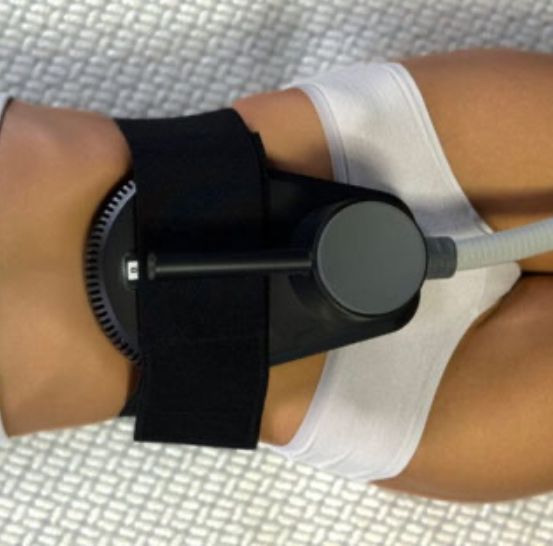 Eine Person liegt auf einem Bett mit einer an der Kniescheibe befestigten Schiene, möglicherweise unterzieht sie sich einer Physiotherapie.