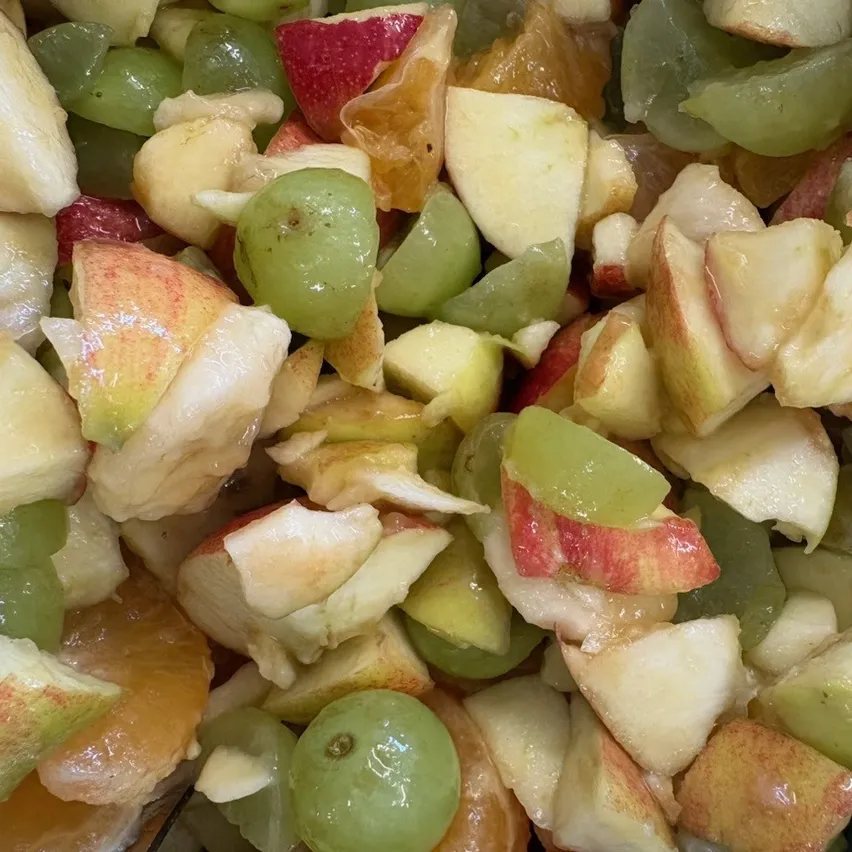 Eine Nahaufnahme eines Obstsalats mit einer Mischung aus Äpfeln, Trauben und Orangen.
