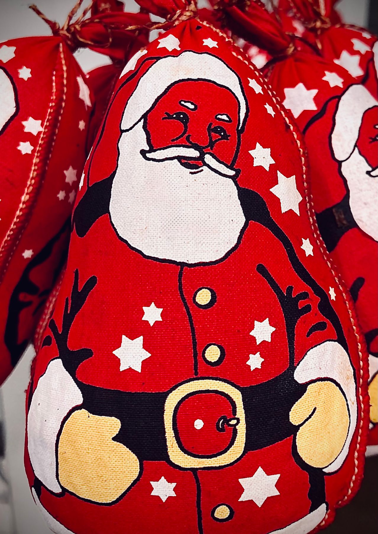 Ein Nahaufnahme von einem roten Weihnachtsmann-Plüschtier mit weißen Sternen und Rentierhörnern. Das Spielzeug hat einen roten Hut, einen weißen Bart und einen Gürtel mit einem roten Knopf.