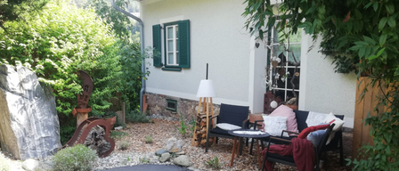 Ein weißes Haus mit grünen Fensterläden und einem Garten mit Tisch und Stühlen.