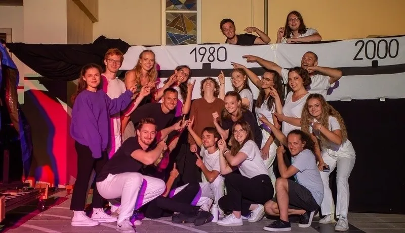Eine Gruppe von Menschen posiert für ein Foto auf einer Bühne mit einem Banner, das 1980 und 2000 steht.