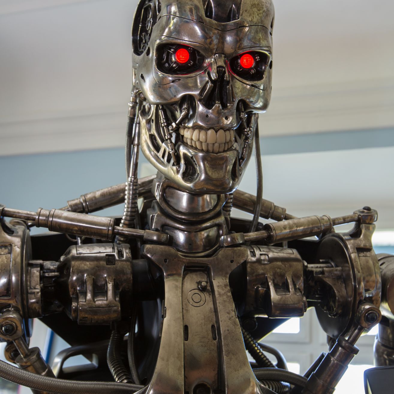 Ein Nahaufnahme eines metallischen Terminator-Roboters mit leuchtend roten Augen und einem mechanischen Gesicht.