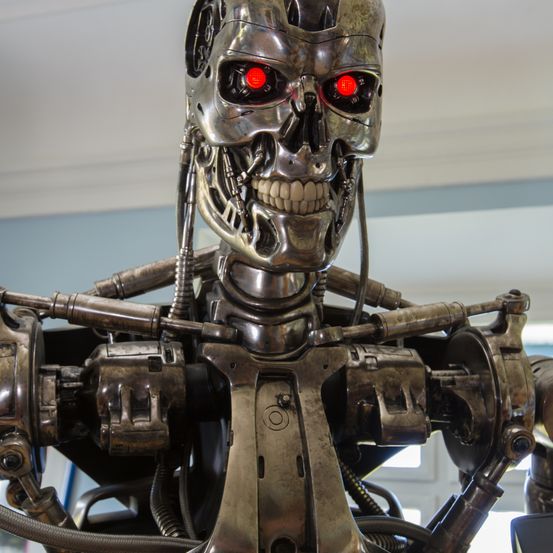 Ein Nahaufnahme eines metallischen Terminator-Roboters mit leuchtend roten Augen und einem mechanischen Gesicht.