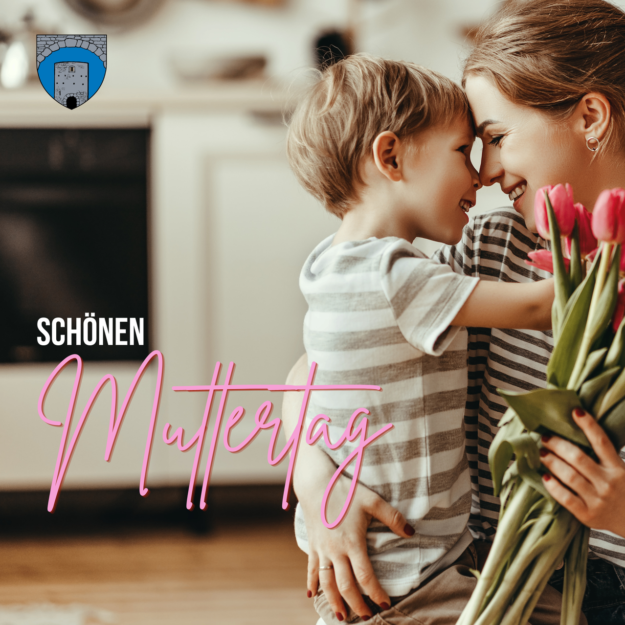 Eine lächelnde Mutter und ein Kind umarmen sich mit Blumen vor einer Küche. Die Worte 'Schönen Muttertag' sind in Pink geschrieben.