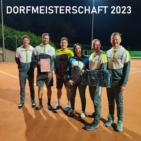 Fünf Personen posieren mit Auszeichnungen auf einem Tennisplatz, der Text darüber lautet Dorfmeisterschaft 2023. Sie halten Pokale und Taschen.