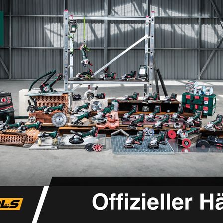 Ein Lager voller Makita-Werkzeuge auf Regalen, mit verschiedenen Maschinen und Geräten, die auf dem Boden gestapelt sind, gekennzeichnet als 'Offizieller Händler'.