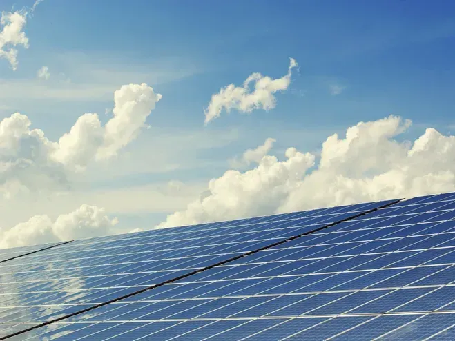 Ein Solarpanel-Array ist unter einem teilweise bewölkten blauen Himmel positioniert und reflektiert Sonnenlicht.