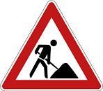 A road sign warning of roadwork ahead, with a person digging using a shovel.