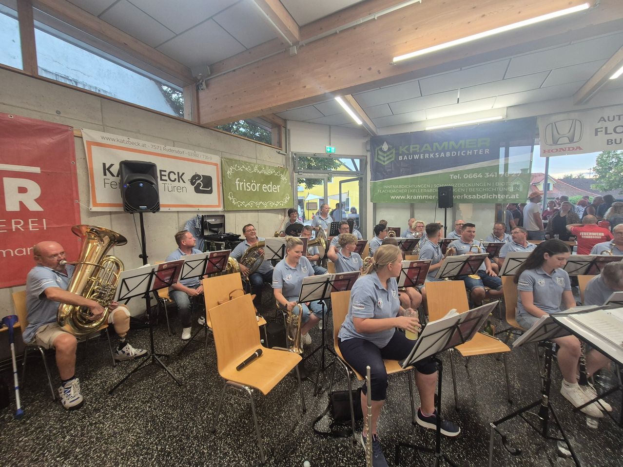 Blaskapelle spielt in Rudersdorf, Burgenland, mit vielen Musikern in blauen Poloshirts.
