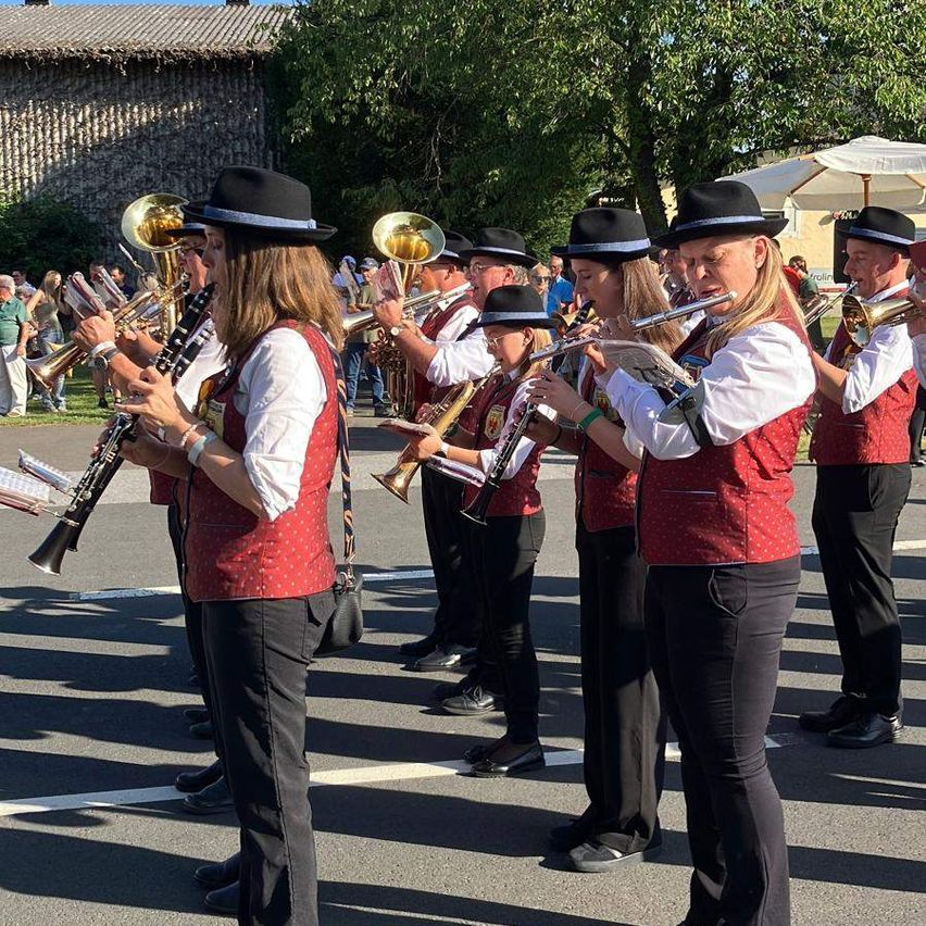 Eine Gruppe von Musikern in roten Westen und schwarzen Hüten spielt auf der Straße und verwendet verschiedene Instrumente.