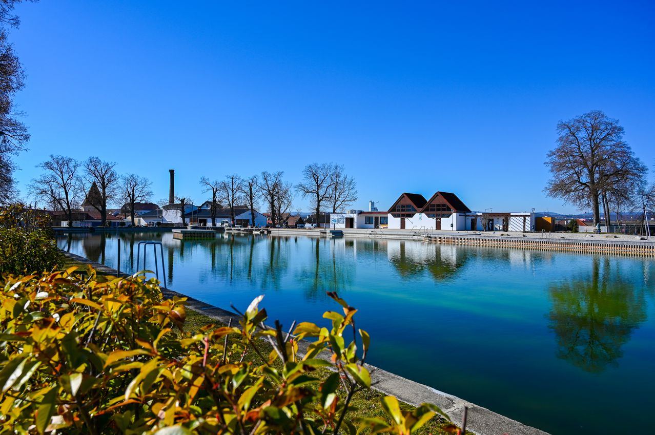 Ein Freibad mit blauem Himmel und mehreren Gebäuden im Hintergrund.