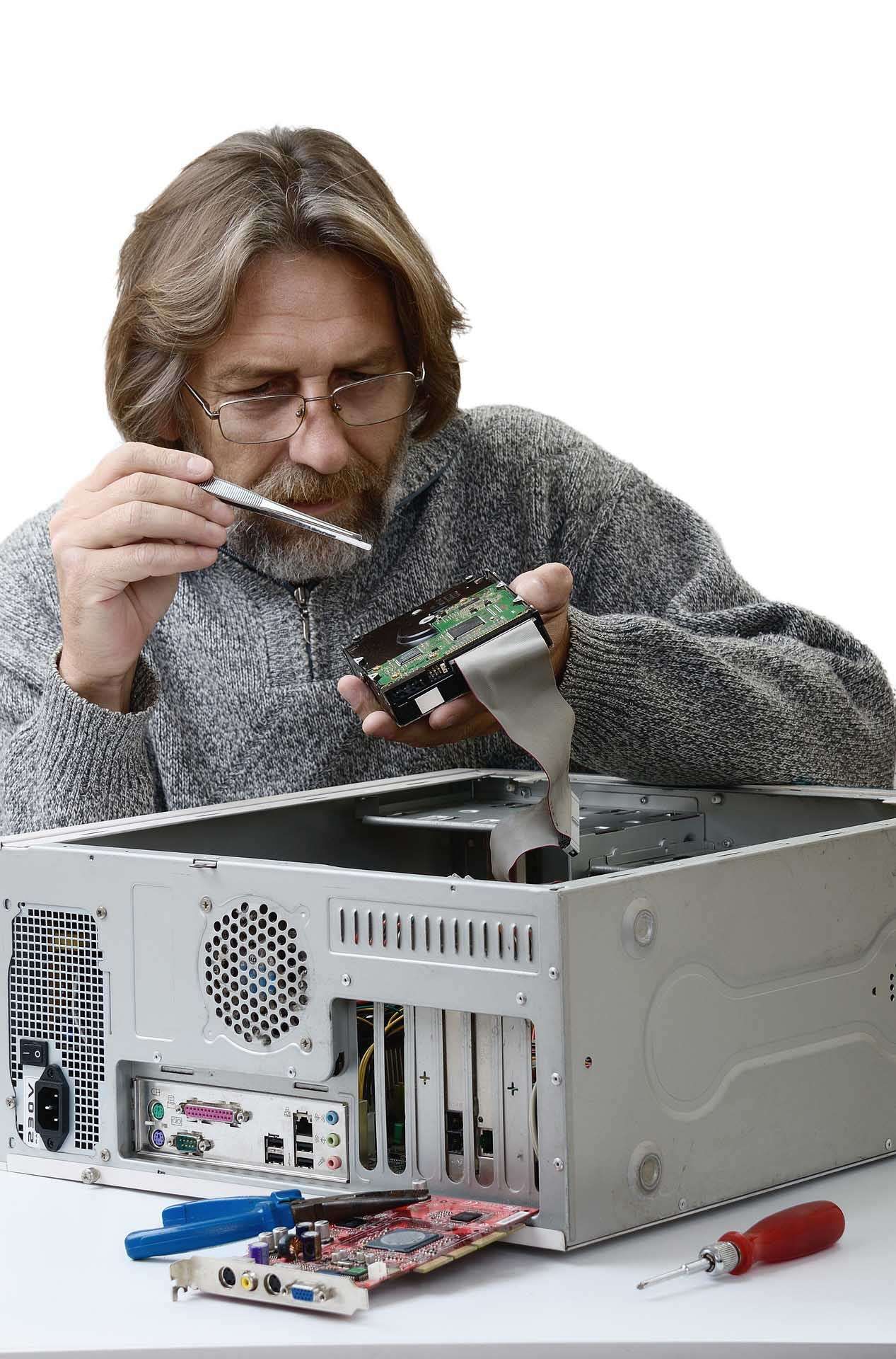Ein Mann mit Brille arbeitet an einem Computer, indem er eine Leiterplatte aus ihrem Gehäuse entfernt.