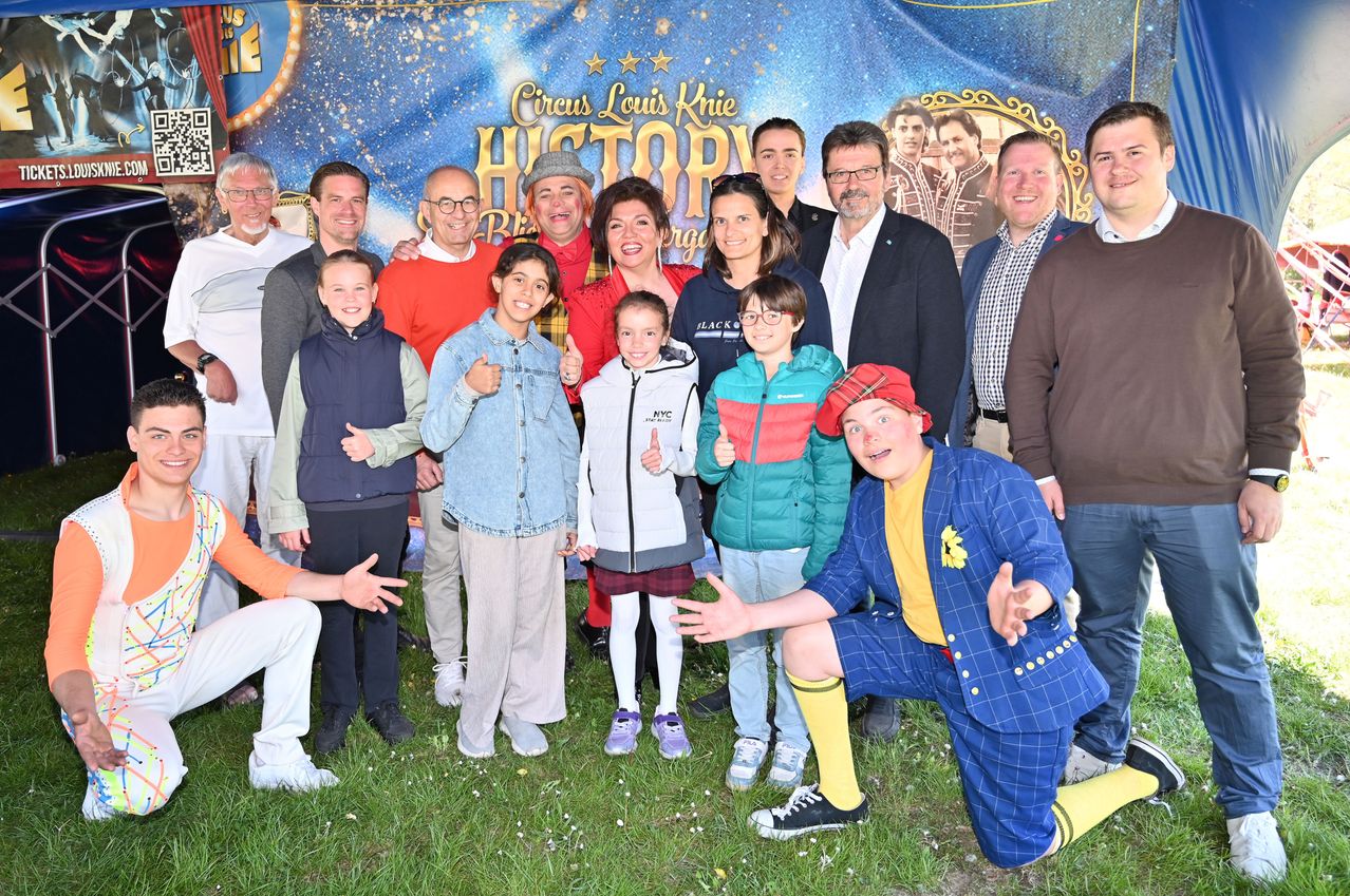 Eine Gruppe von Menschen, darunter Kinder, posiert für ein Foto vor einem Banner mit der Aufschrift Circus Louis Knie Geschichte.