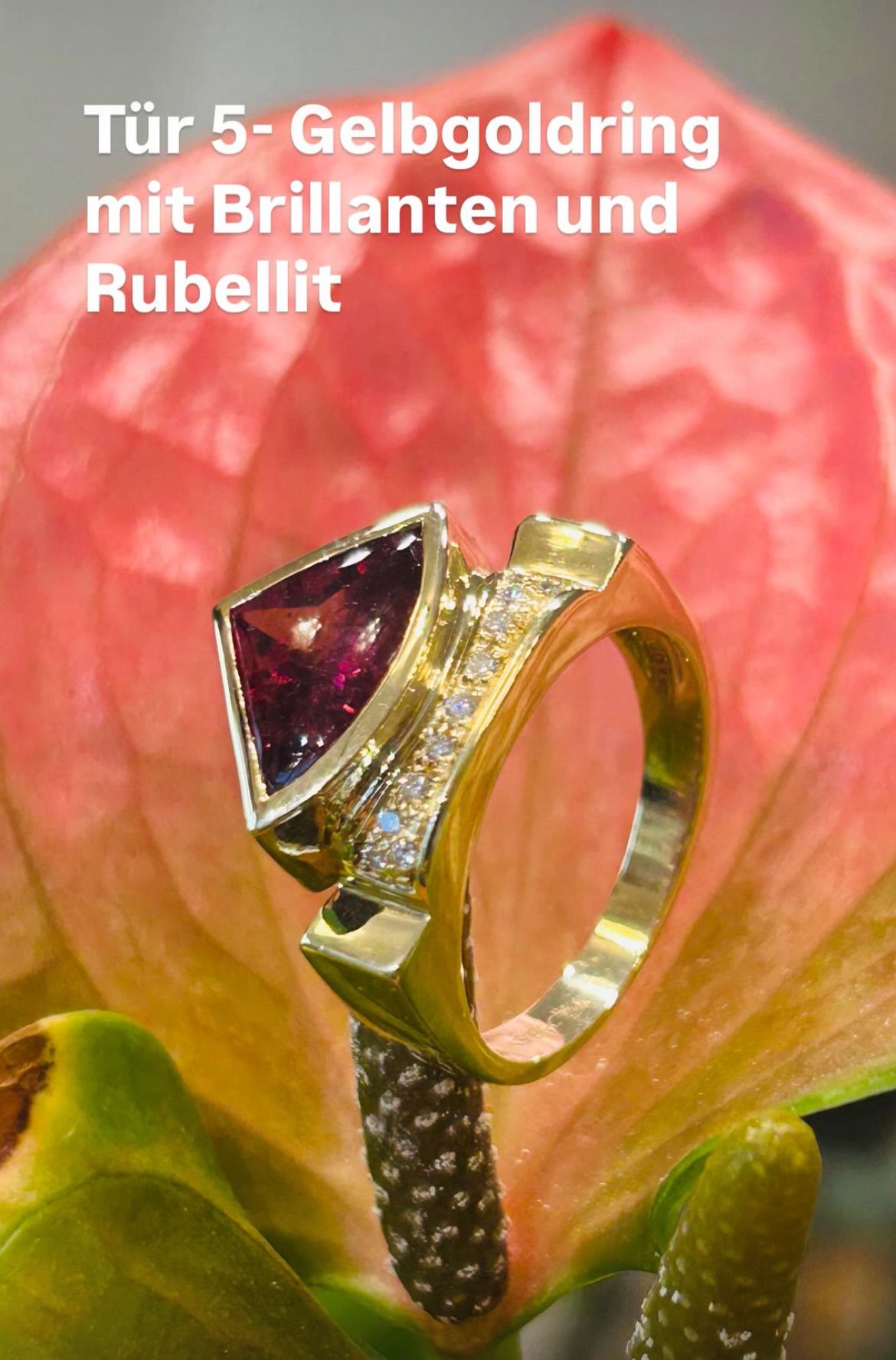 Ein goldener Ring mit einem großen rot-pinkfarbenen Edelstein und Diamanten sitzt auf einer rosa Blume. Das Wort Rubellit steht über dem Ring.