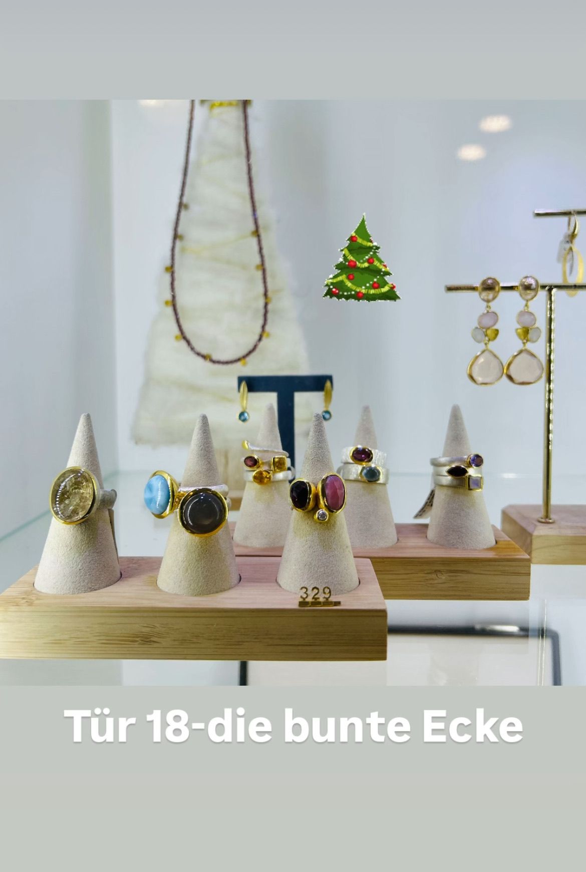 Eine Ausstellung von Edelsteinringen und Ohrringen mit einem Weihnachtsbaum im Hintergrund.