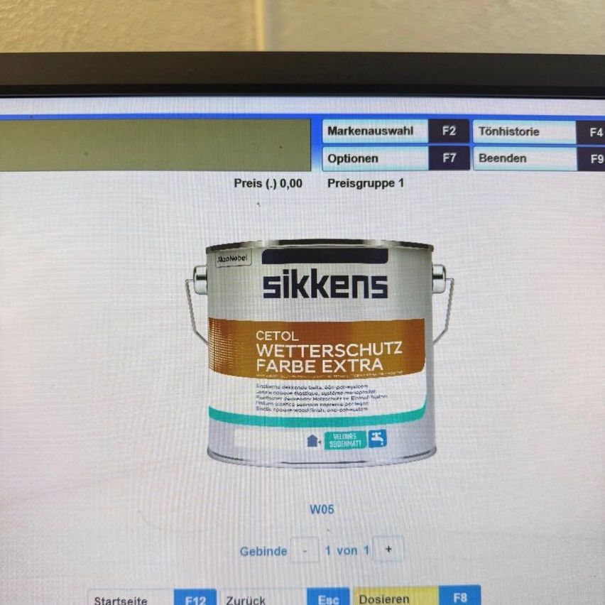 Ein Computerbildschirm zeigt eine Farbdose mit der Aufschrift 'Sikkens Cetol Wetterschutz Farbe Extra'. Die Dose hat einen braunen Deckel mit dem Markennamen 'Sikkens'. Unter dem Deckel befindet sich ein blaues Etikett mit weißem Text. Der Bildschirm zeigt auch eine Navigationsleiste mit Optionen wie 'Markenauswahl', 'Optionen' und 'Beenden'.