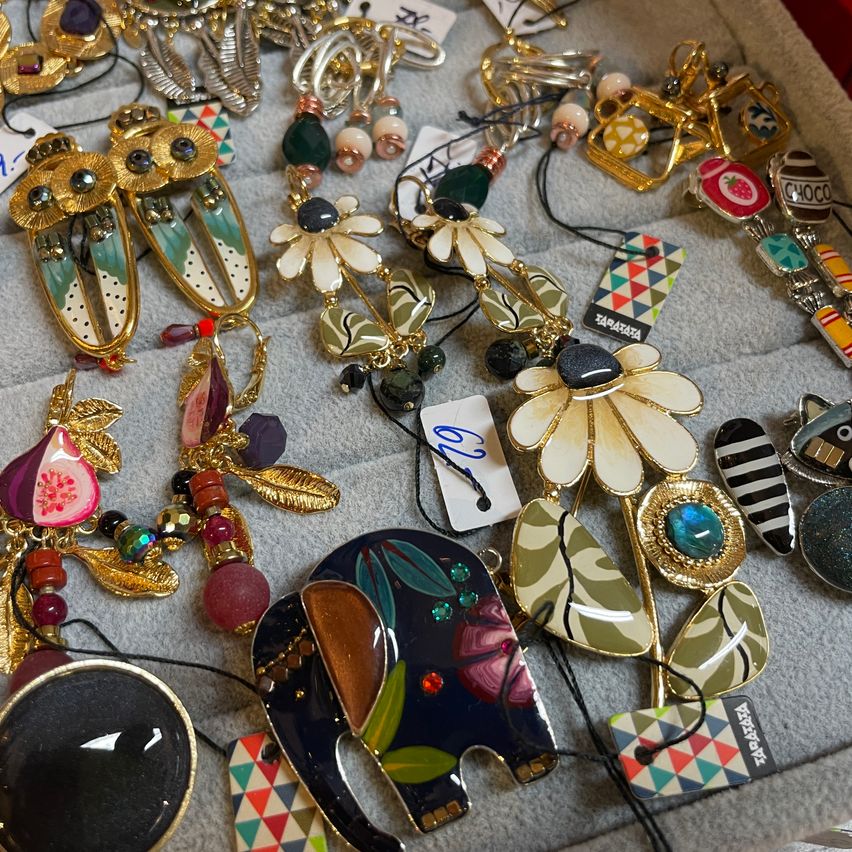 Eine Sammlung bunter Schmuckstücke mit Blumen-, Eulen- und Elefantendesigns. Die Stücke bestehen aus Gold, Grün und Schwarz mit Perlen und Edelsteinen.