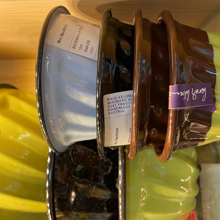 Ein Nahaufnahme eines braunen Keramikobjekts mit weißem Text und einem lila Aufkleber. Der Aufkleber sagt 'mini form'. Es hat eine glänzende Oberfläche und scheint ein dekoratives Element zu sein.