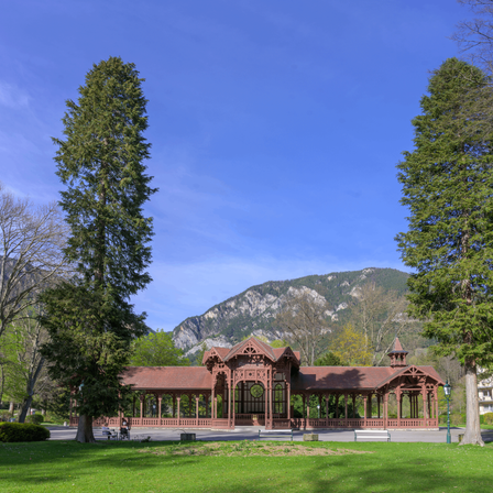 Ein Pavillon in einem Park mit einem Berg im Hintergrund an einem klaren Tag.