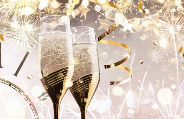 Zwei Champagnerflöten mit goldenen Rändern und Blasen stehen vor einer Uhr und Feuerwerk.