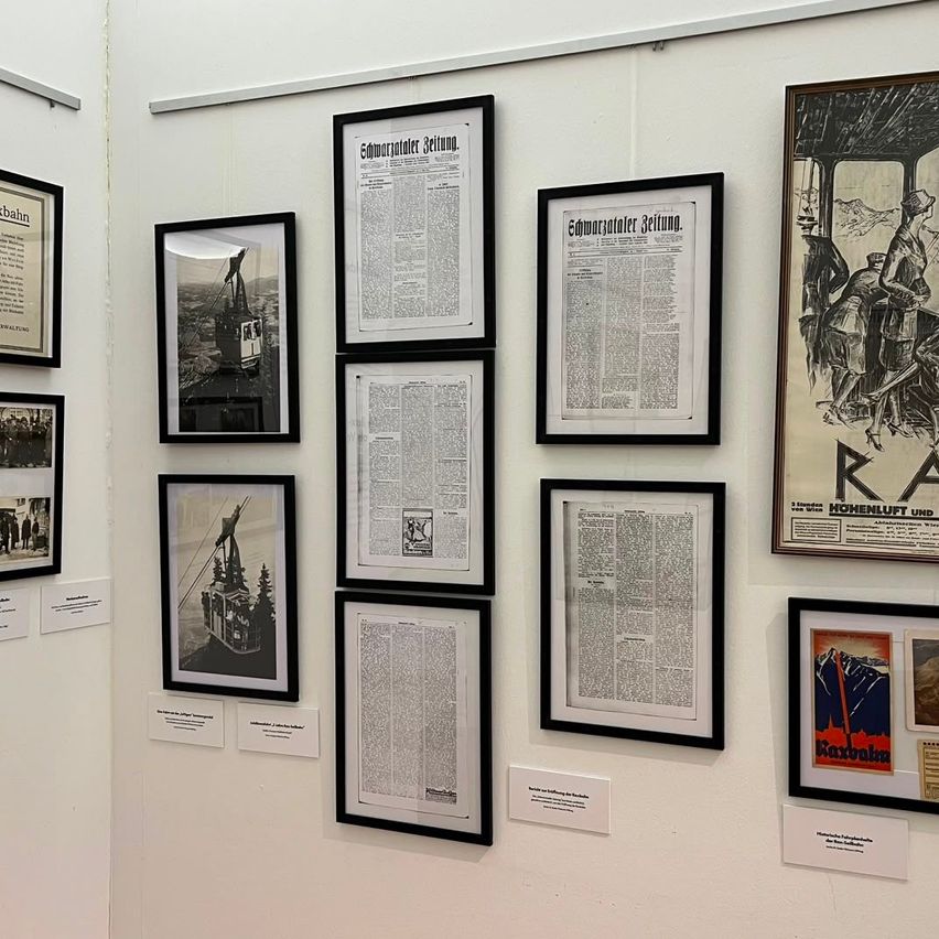 A wall with several framed documents and posters, including one with a man and woman in vintage attire.
