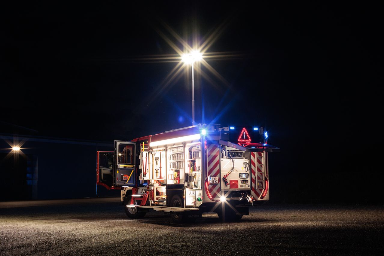 A fire truck is parked with its lights on, illuminating the dark area at night.