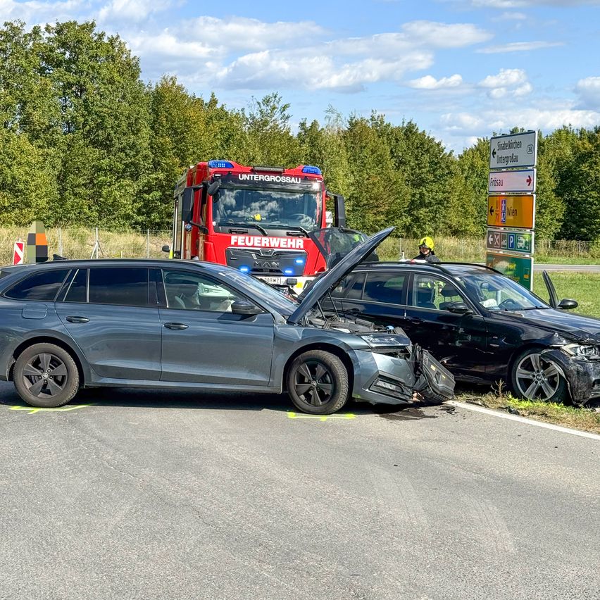 Zwei Autos sind an der Straßenseite beschädigt, ein Feuerwehrwagen ist in der Nähe.