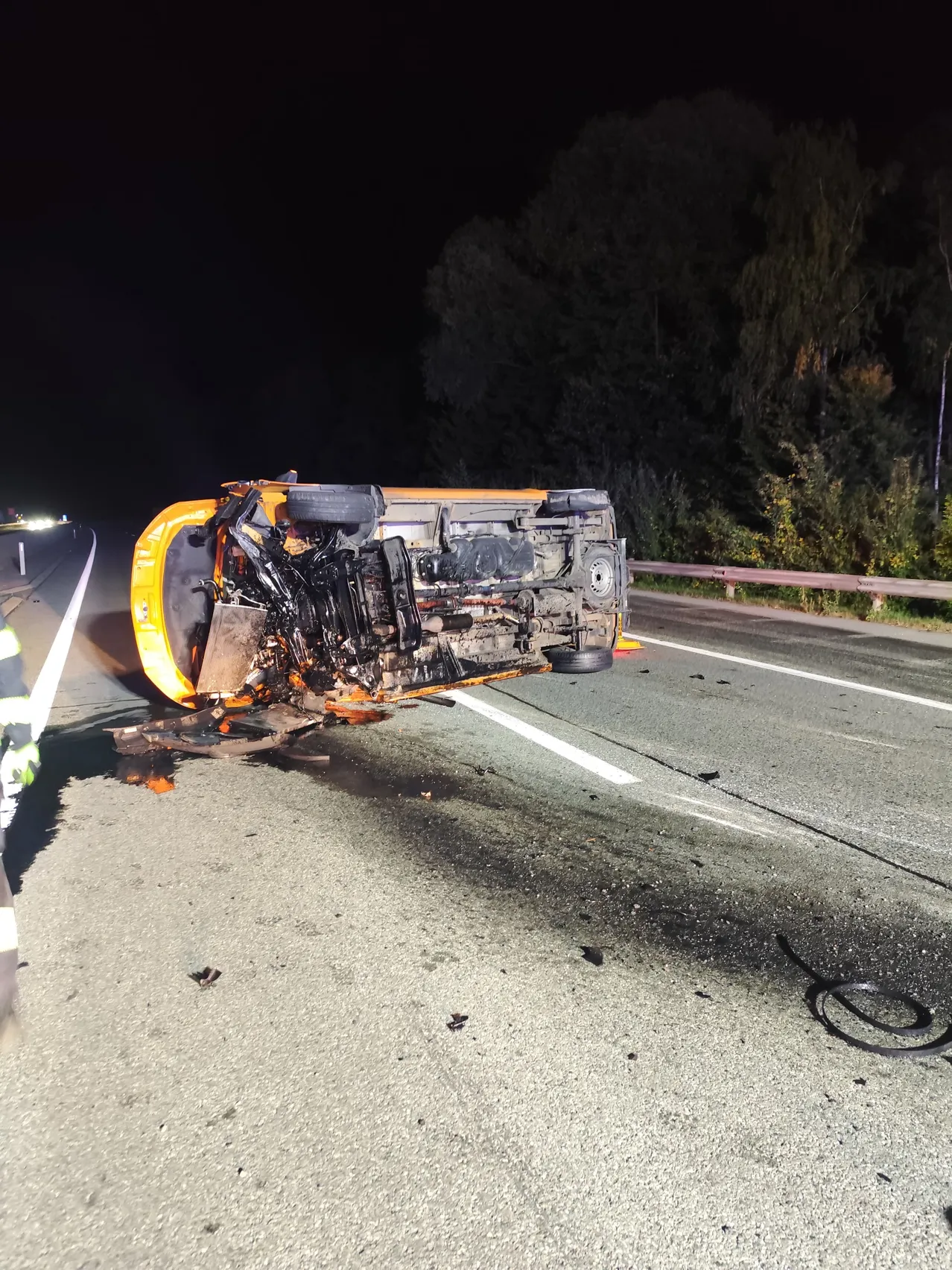 Ein gelber Schulbus liegt auf der Seite auf einer dunklen Straße in der Nacht.