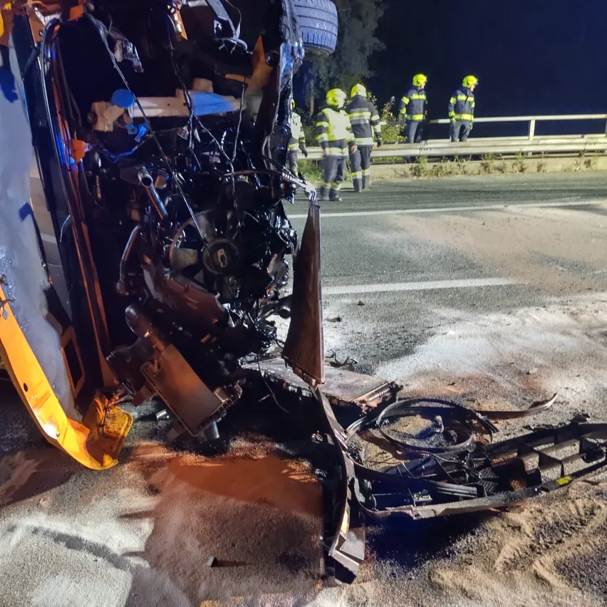 Ein Schulbus war in einen schweren Unfall verwickelt, wobei die Front stark beschädigt und Teile des Busses auf der Straße verstreut sind.