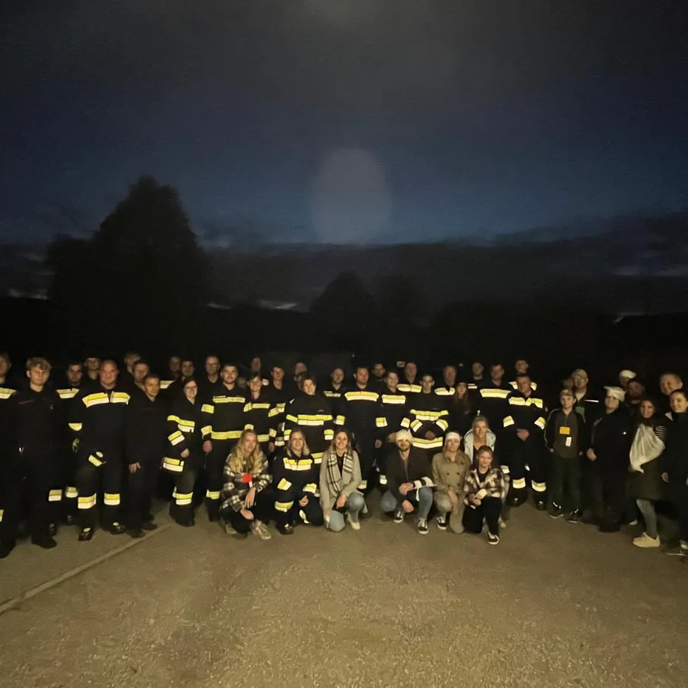 Eine Gruppe von Feuerwehrleuten und Freiwilligen posiert nachts für ein Foto.