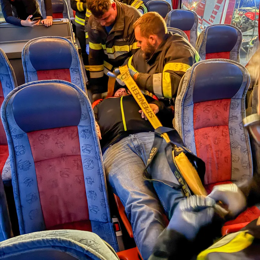 Ein Mann wird von zwei Feuerwehrleuten auf einem Bus betreut.