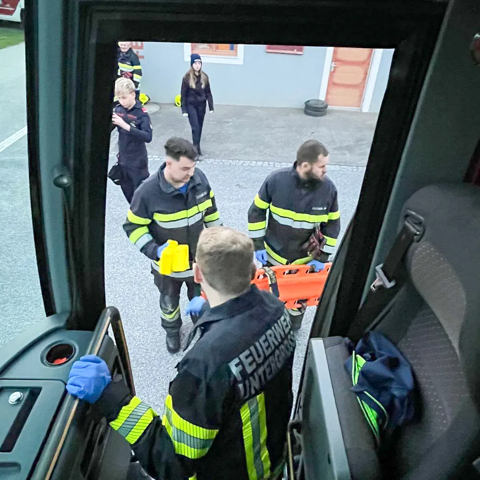 Eine Gruppe von Feuerwehrleuten bereitet sich darauf vor, einen Patienten auf einer Trage aus einem Krankenwagen zu transportieren.