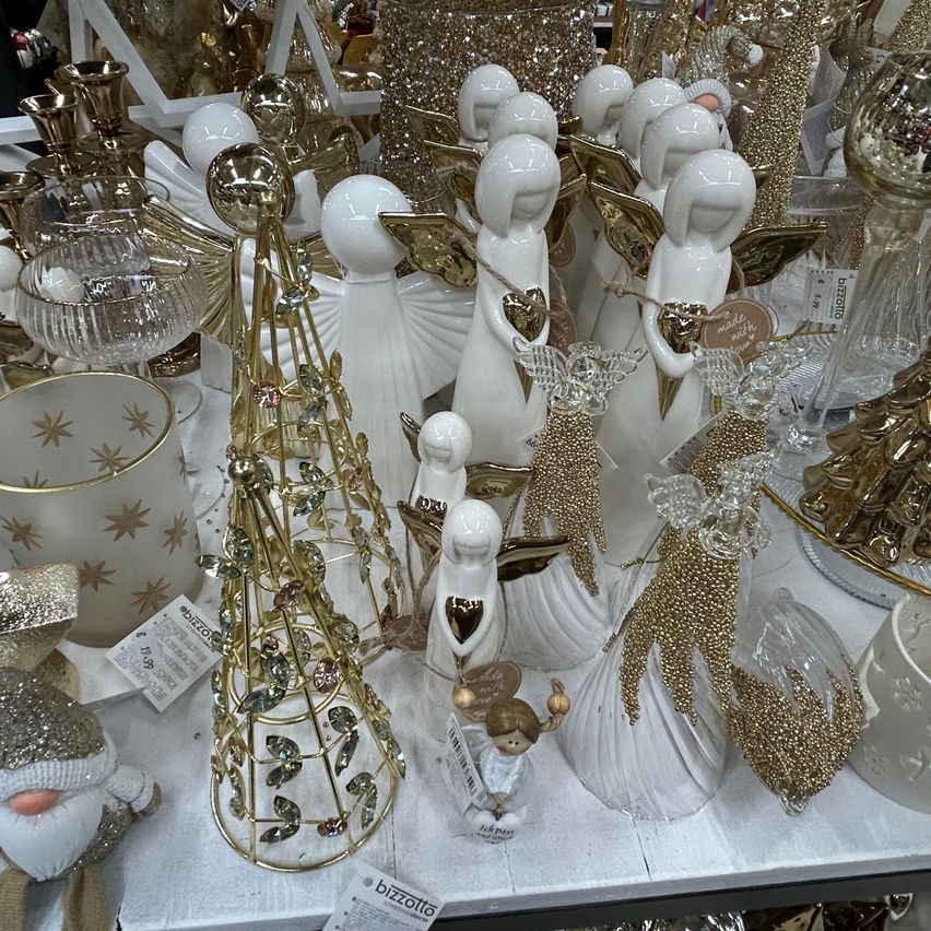 Eine weiße und goldene Engel-Figur-Ausstellung auf einem Tisch, mit Ornamenten, Glas und anderen Gegenständen.