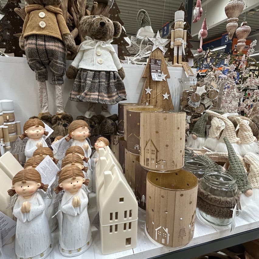 Ein Laden präsentiert eine Sammlung von Weihnachtsdekorationen, darunter Engelsfiguren, hölzerne Kerzenhalter und verschiedene festliche Figuren.