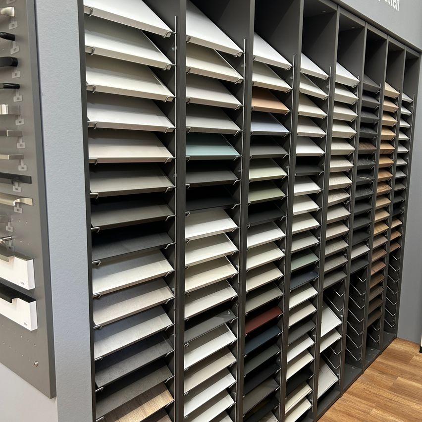 Eine Ausstellung verschiedener Farbmuster, die jeweils auf Regalen montiert sind. Die Farben reichen von hellen bis zu dunklen Tönen.