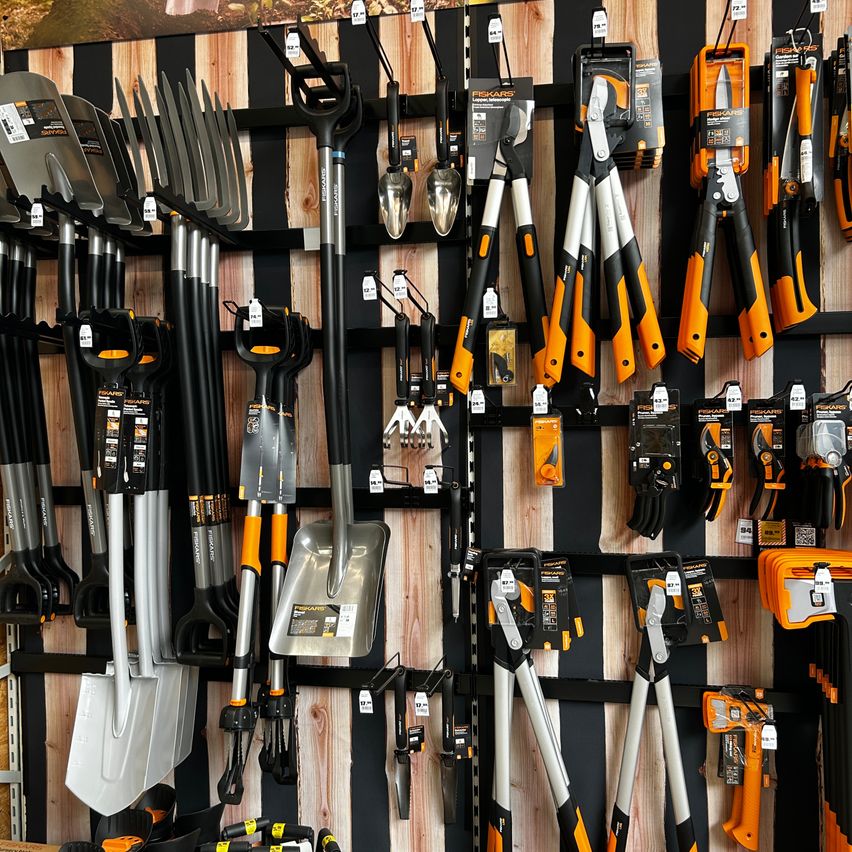 A wall displaying a variety of gardening tools, including shovels, rakes, and pruners, all neatly organized and hanging on hooks.