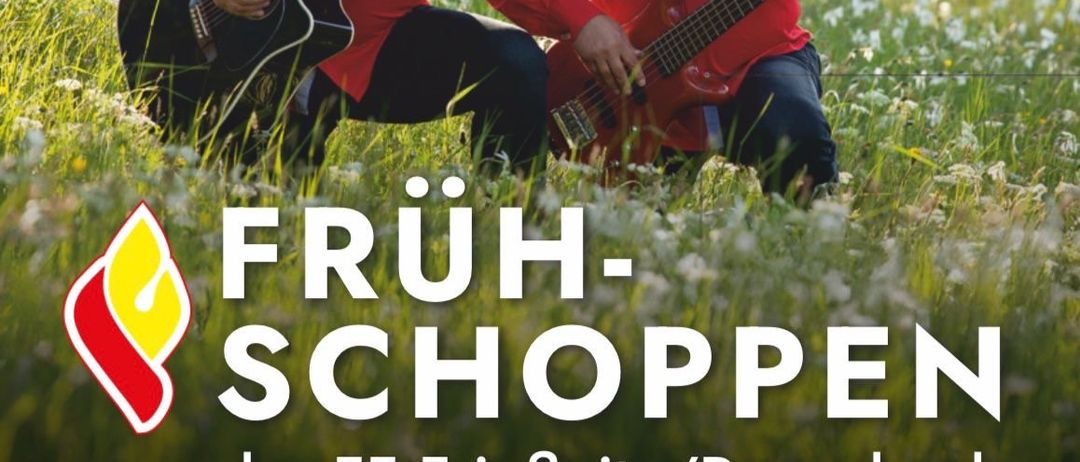 Zwei Männer in roten Hemden sitzen auf dem Gras und spielen Gitarre. Veranstaltung mit dem Titel 'Fruh-Schoppen der FF Friefnitz/Rosenbach' mit Datum 22. Juni 2025. Zeit ist 10:15 Uhr bei der Feuerwehr in Schlaten.