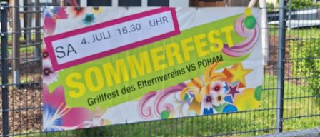 Ein buntes Plakat für ein Sommerfest hängt an einem Zaun und zeigt Datum und Uhrzeit auf Deutsch.